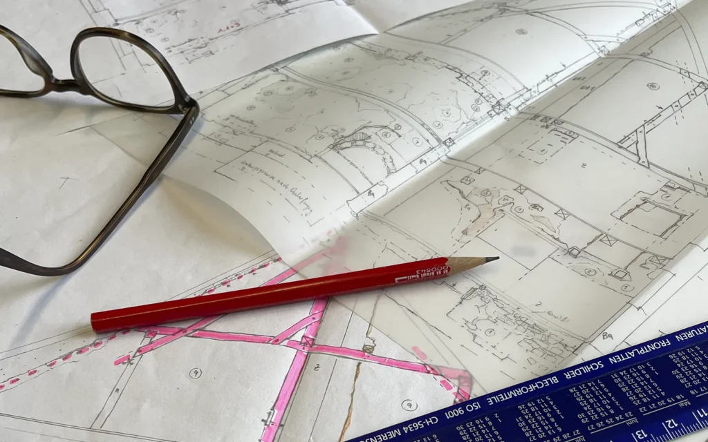 Planzeichnungen einer historischen Gebäudeaufnahme mit Brille, Bleistift und Messlineal – Arbeitsmaterial der bauhistorischen Analyse und Dokumentation