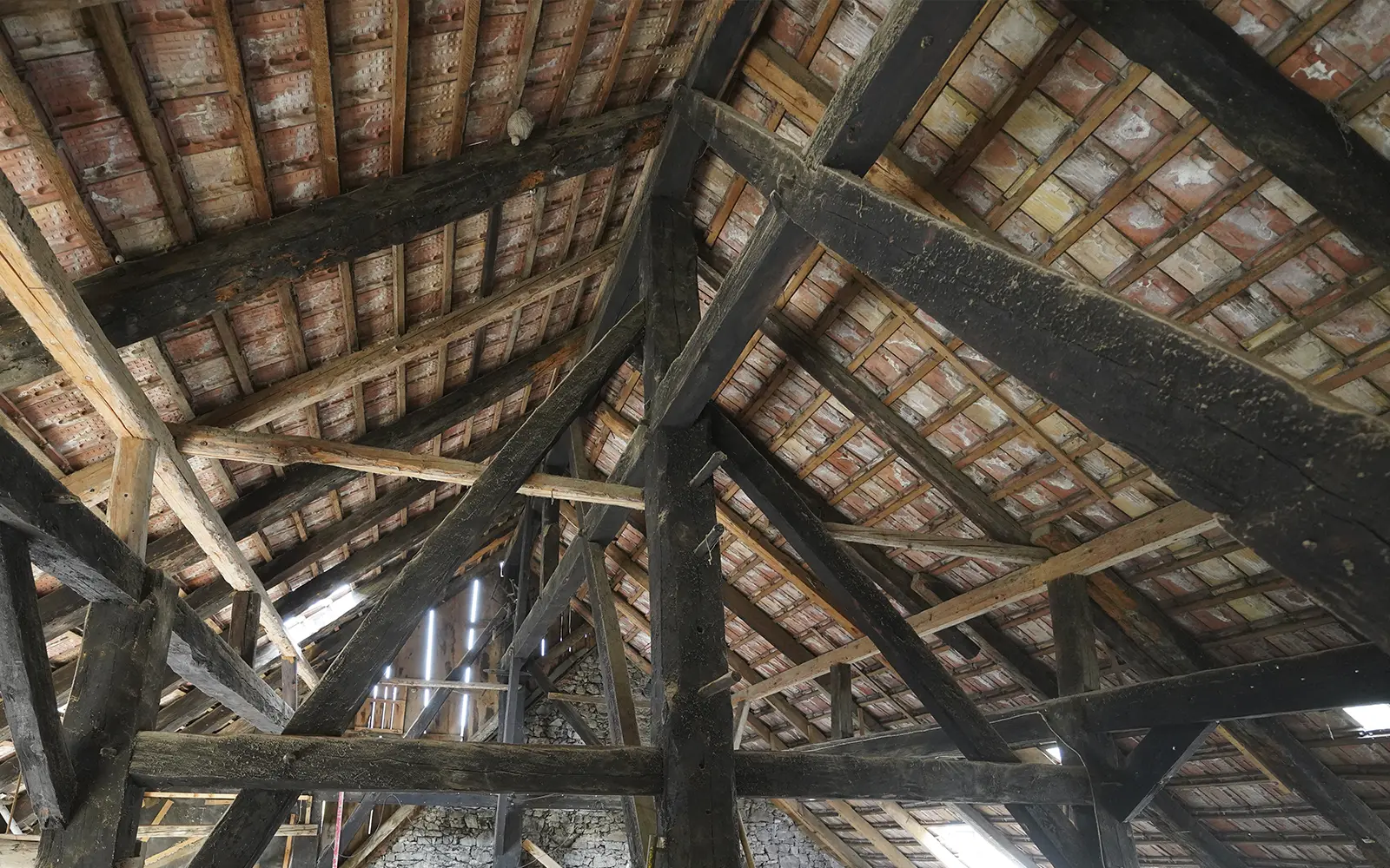 Historischer Dachstuhl mit Holzbalken und Ziegeldeckung als Beispiel für eine dendrochronologische Untersuchung zur Bestimmung des Holzalters